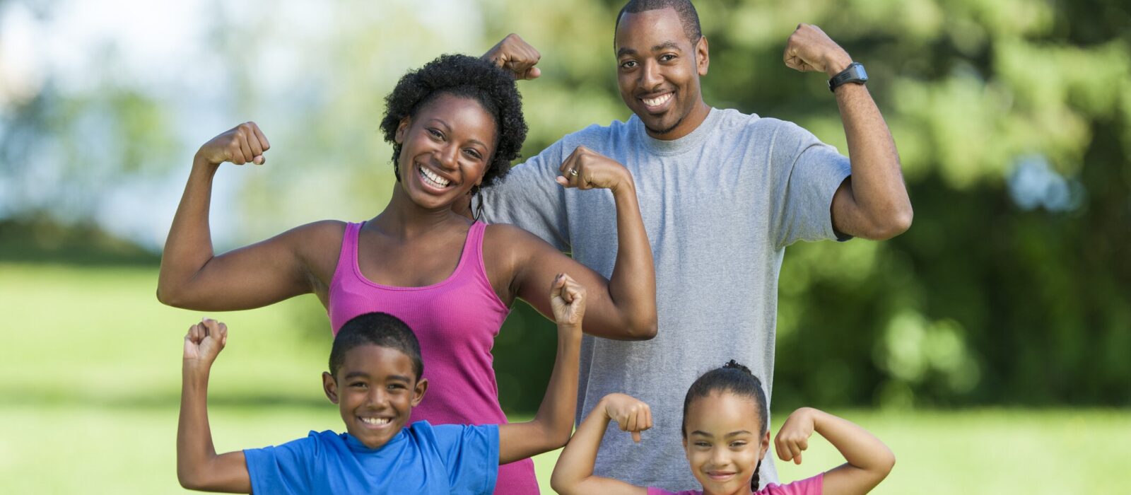 Smiling family flexing muscles outdoors